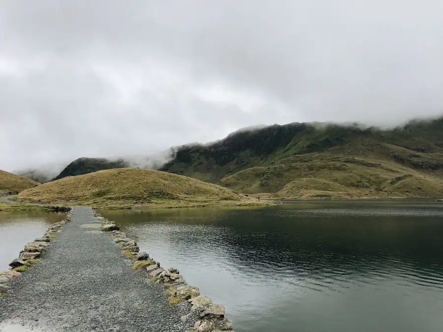 Serene view of a tranquil pathway alongside a lake in Snowdonia, Wales.