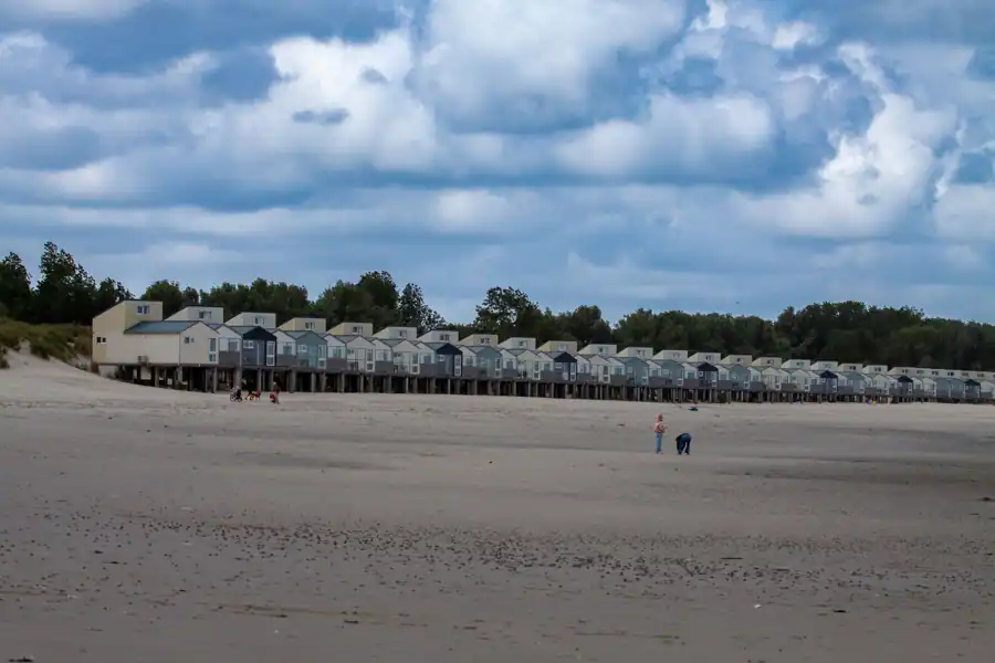 Scenic view of beach houses along the shore in Kamperland under a cloud-filled sky.