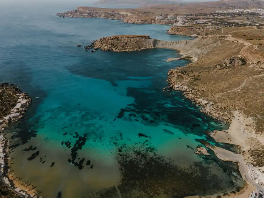 Breathtaking aerial shot of the Mgarr coastline with crystal blue waters and rugged landscape in Malta.