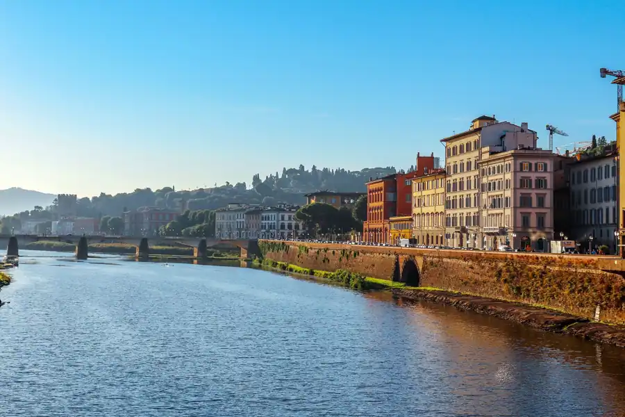 Scenic daytime view of the Arno River with historic buildings in Florence, Italy.